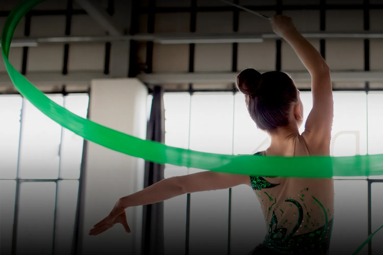 Gimnasta de Nueva Chicago realizando una rutina con cinta verde en el gimnasio