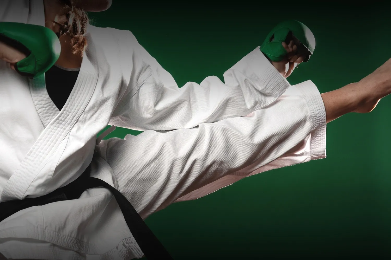 Practicante de taekwondo con casco y guantes verdes ejecutando una patada alta