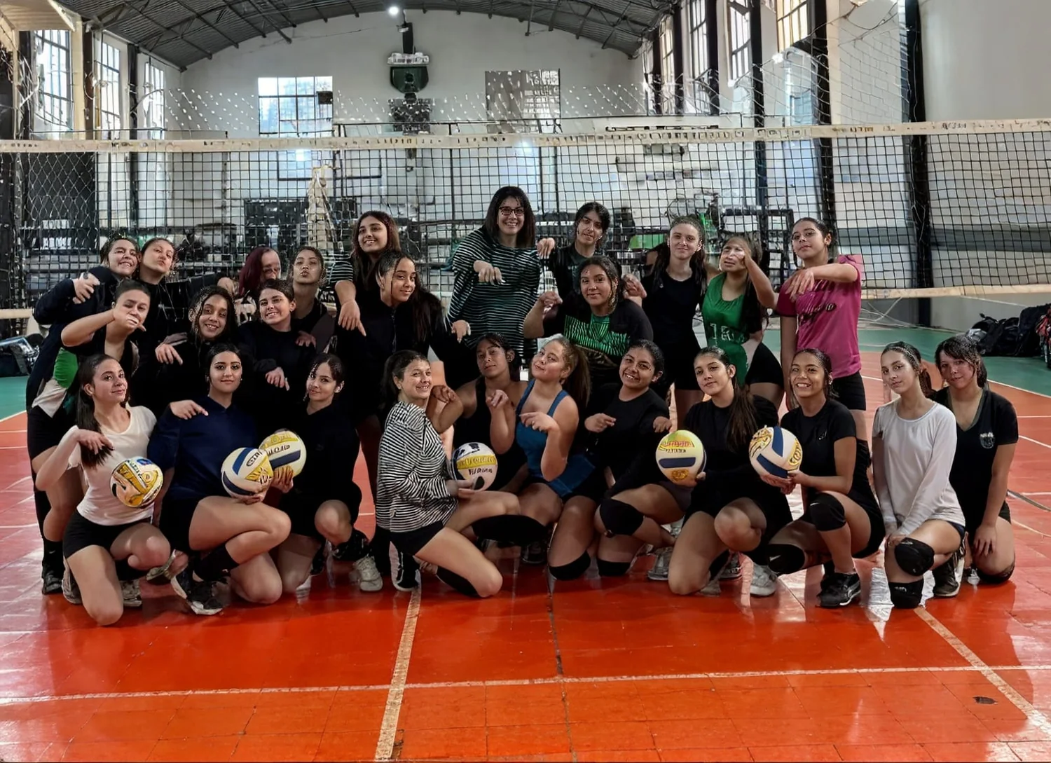 Equipo de vóley de Nueva Chicago posando con pelotas en el gimnasio